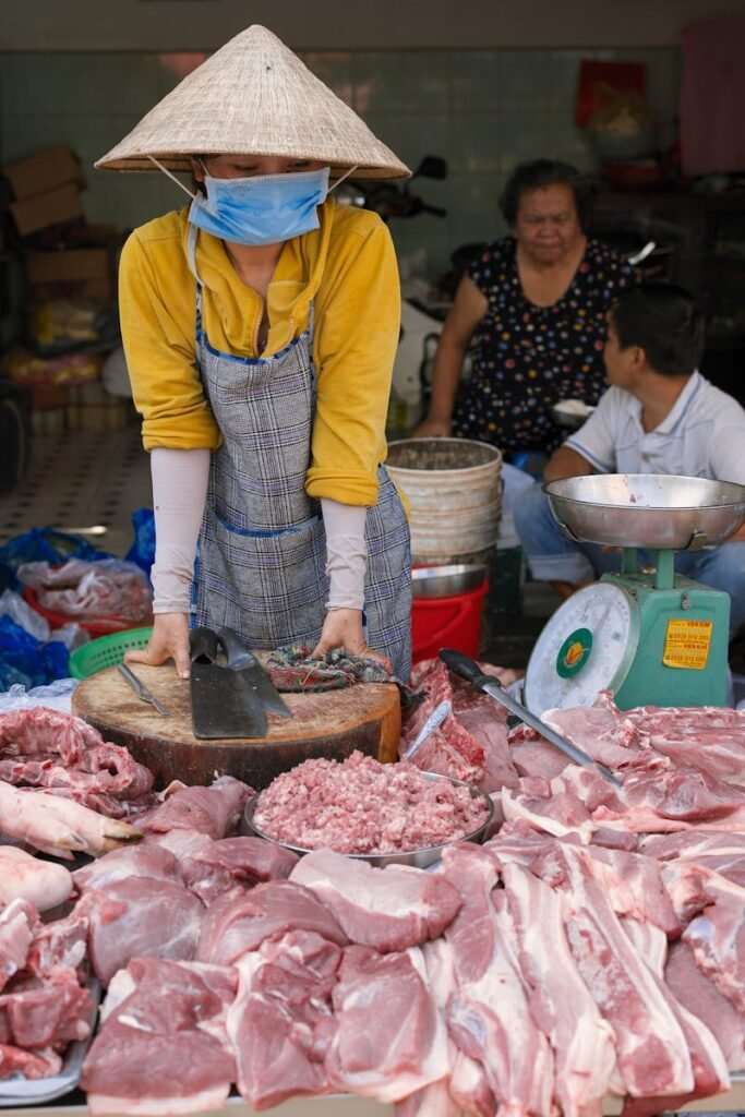 Asian woman selling meat at a traditional wet market in Ho Chi Minh City, Vietnam.