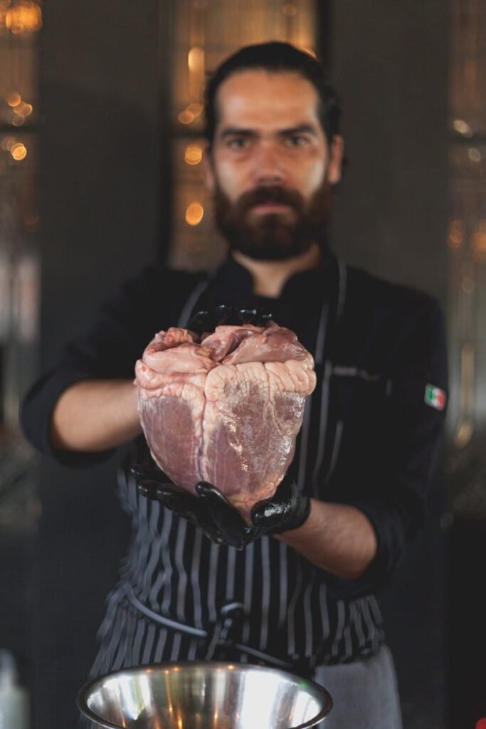 Carnicerías en Córdoba - Chef holding raw meat in kitchen, focusing on quality ingredient for a gourmet dish.